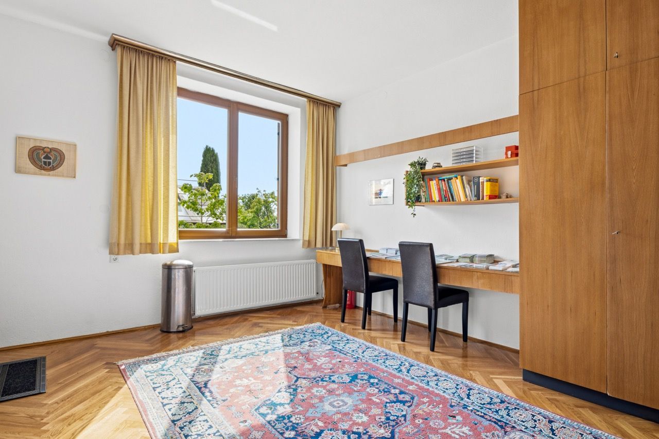 Arbeitszimmer mit Schreibtisch, Einbauschrank aus Holz, Fenster und Teppich
